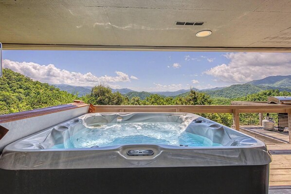 A hot tub with a view of mountains and greenery.
