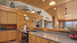 A spacious kitchen with wooden cabinets, a granite countertop, and a large window offering a view of the outdoors.