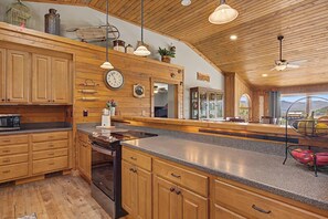 Una cocina amplia con gabinetes de madera, encimera de granito y un ventanal con vistas al exterior.
