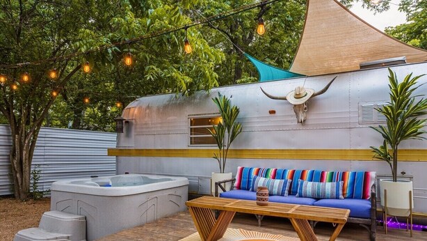 An outdoor living area with a sofa, a wooden table, and a hot tub. - The Austin LoveStream! New Hot Tub, Full Bathroom, Deck & Grill! (Austin)
