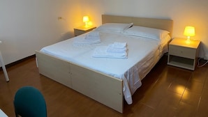 A single bed with a wooden frame and white bedding, two bedside lamps, and a small bedside table. - RES Falena apartment within walking distance of the hospital and the city center (Padova)