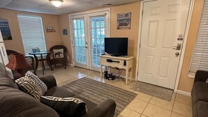 A living room with a sofa, a TV on a stand, a dining table with chairs, and a door with a 'No Entry' sign. - Lower Level, Apartment Style Beach House! (Surfside Beach)