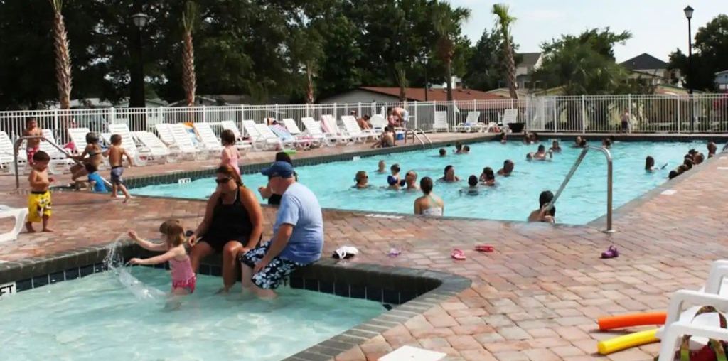 Un área de piscina con varias piscinas y tumbonas.
