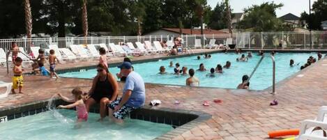 A swimming pool area with multiple pools and lounge chairs.