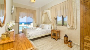 Een slaapkamer met een bed, nachtkastje, lamp en uitzicht op zee.