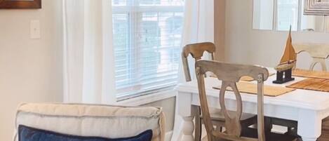 Un comedor con una mesa blanca, sillas de madera y una lámpara de araña.