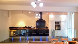 Una cocina moderna con una isla central, electrodomésticos integrados y un comedor con mobiliario de madera.