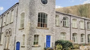 Un edificio de piedra con una torre de reloj, varias ventanas y una puerta azul.