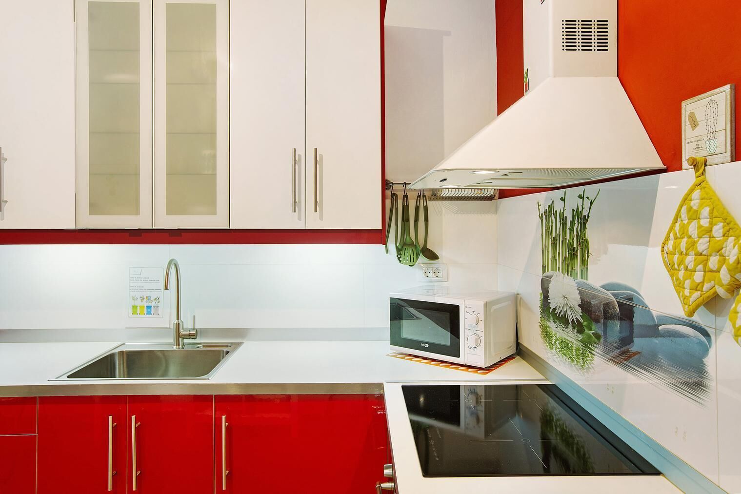 Une cuisine moderne avec des meubles blancs, un plan de travail rouge, un four à micro-ondes encastré et une cuisinière.
