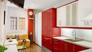 Una cocina compacta con armarios rojos, una encimera blanca y un horno integrado.