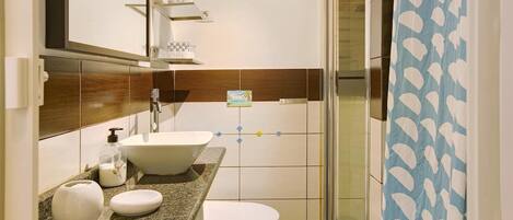 Un baño con lavamanos, inodoro y ducha.