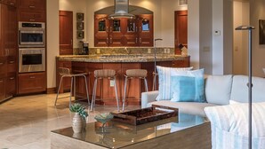 A modern kitchen with built-in appliances, a bar area, and a seating area with a glass coffee table.