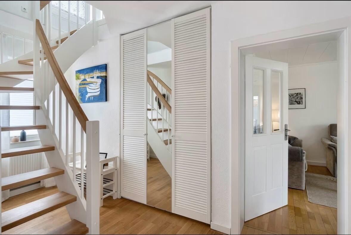 Un escalier avec des rampes blanches et des marches en bois menant à un palier.