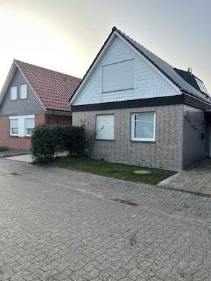 Ein zweistöckiges Haus mit Backsteinfassade, Ziegeldach und kleinem Vorgarten.