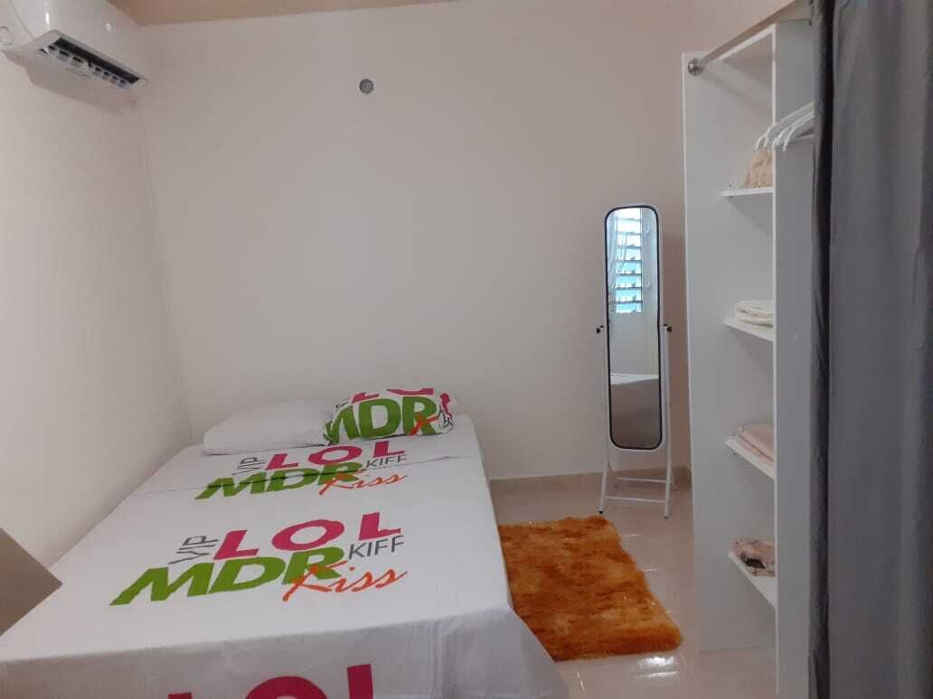 A small, clean room with a bed, a mirror, and a wardrobe.