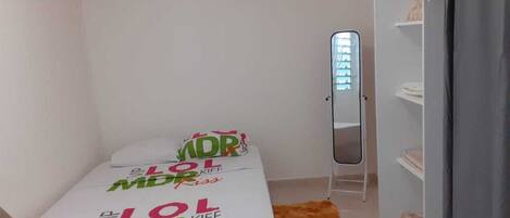 A small, clean room with a bed, a mirror, and a wardrobe.