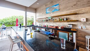 A bar area with a long counter, bar stools, and a variety of bottles. - Villa Akumal, A Peaceful Space for 6 with Private Jacuzzi *  Steps to the Beach! (Akumal)