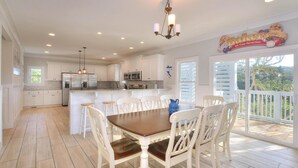 Una cocina amplia con armarios blancos, una isla central con taburetes y una mesa de comedor con sillas.