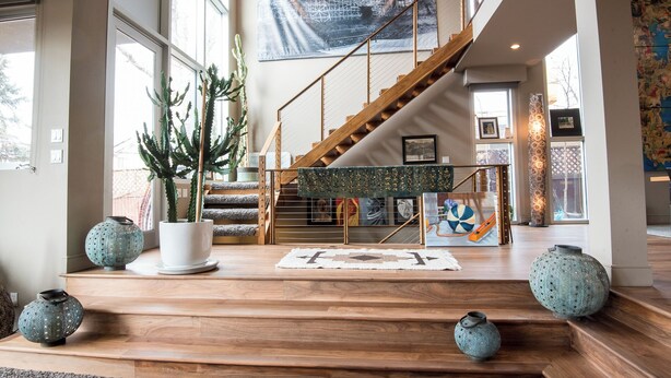 Un espacio habitable amplio con una escalera de madera, ventanas grandes y vistas al exterior.