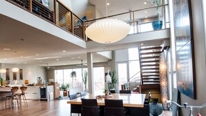 Un interior espacioso y moderno con un amplio comedor, una cocina y una escalera que sube a un nivel superior.
