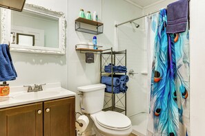 A bathroom with a white sink, a toilet, a mirror with an ornate frame, and a shower curtain with a peacock feather design. - Pet-Friendly Canyon Lake Studio: Fish, Boat, Relax (Canyon Lake)