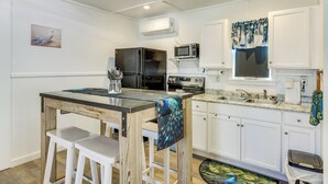 A compact kitchen with white cabinets, a refrigerator, microwave, and a peacock-themed tablecloth. - Pet-Friendly Canyon Lake Studio: Fish, Boat, Relax (Canyon Lake)