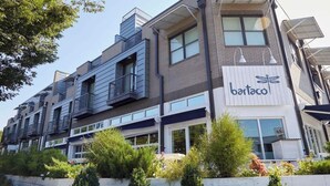 A modern multi-story building with a restaurant named "bartaco" on the ground floor.