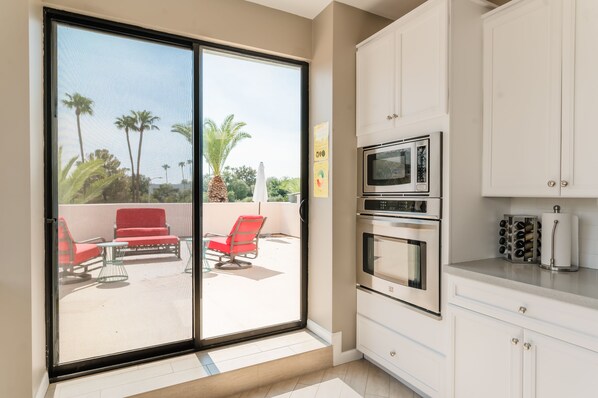 A modern kitchen with white cabinets, a microwave, and an oven.