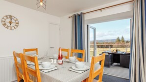 Un coin repas avec une table dressée pour quatre personnes, une bouteille de champagne et une vue sur l’extérieur.