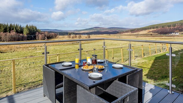 Une table à manger installée à l’extérieur, offrant une vue panoramique sur des collines et des champs.