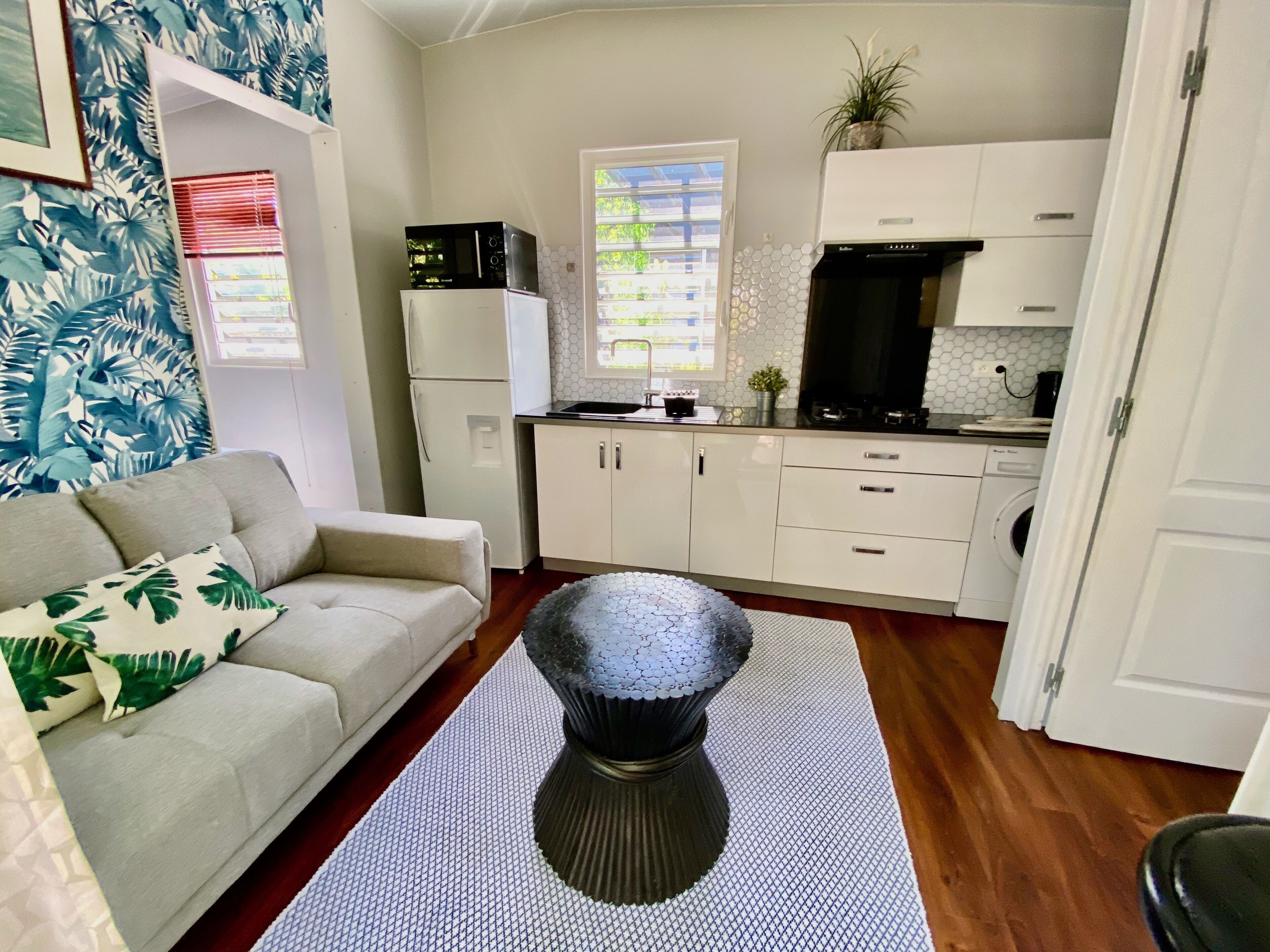 A compact living space with a kitchenette, a sofa, and a coffee table.