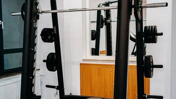 Un gimnasio con una estructura para sentadillas, banco de pesas y diferentes discos de pesas.