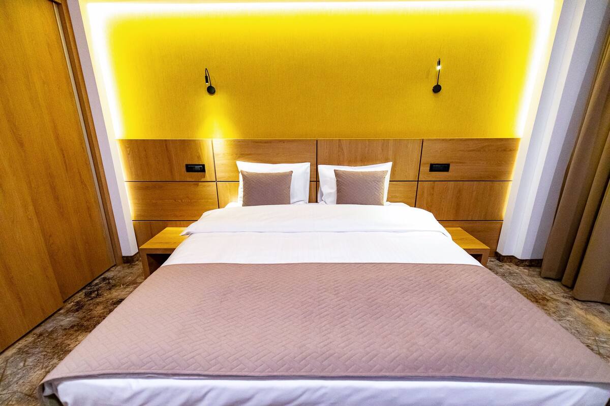 A hotel room with a large bed, wooden headboard, and bedside tables.