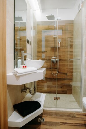 A modern bathroom with a glass-enclosed shower, a white sink, and a black towel. - Grand View Hotel & Suites Copou (Iasi)
