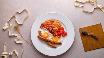 A plate of breakfast food including eggs, bacon, beans, and tomatoes.