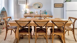 Un comedor con una mesa y sillas de madera, un espejo y elementos decorativos.