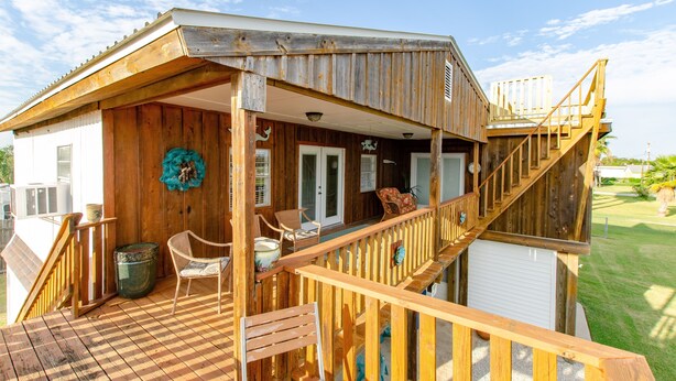 Una cabaña de madera con un porche, mobiliario exterior y una escalera.