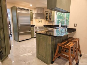 Una cocina moderna con electrodomésticos de acero inoxidable, una isla central y taburetes de madera.