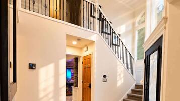 A spacious interior with a marble floor, a grand staircase, and a modern light fixture.