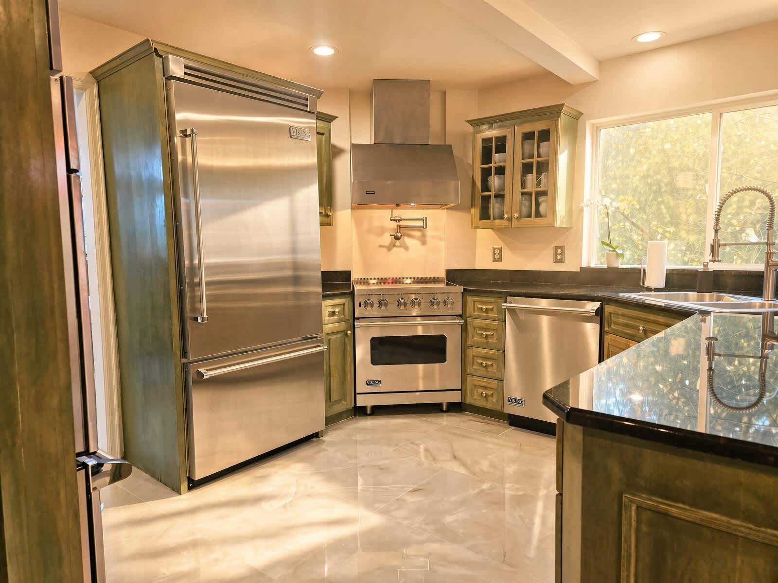 A kitchen with stainless steel appliances, a central island, and a window with a view.