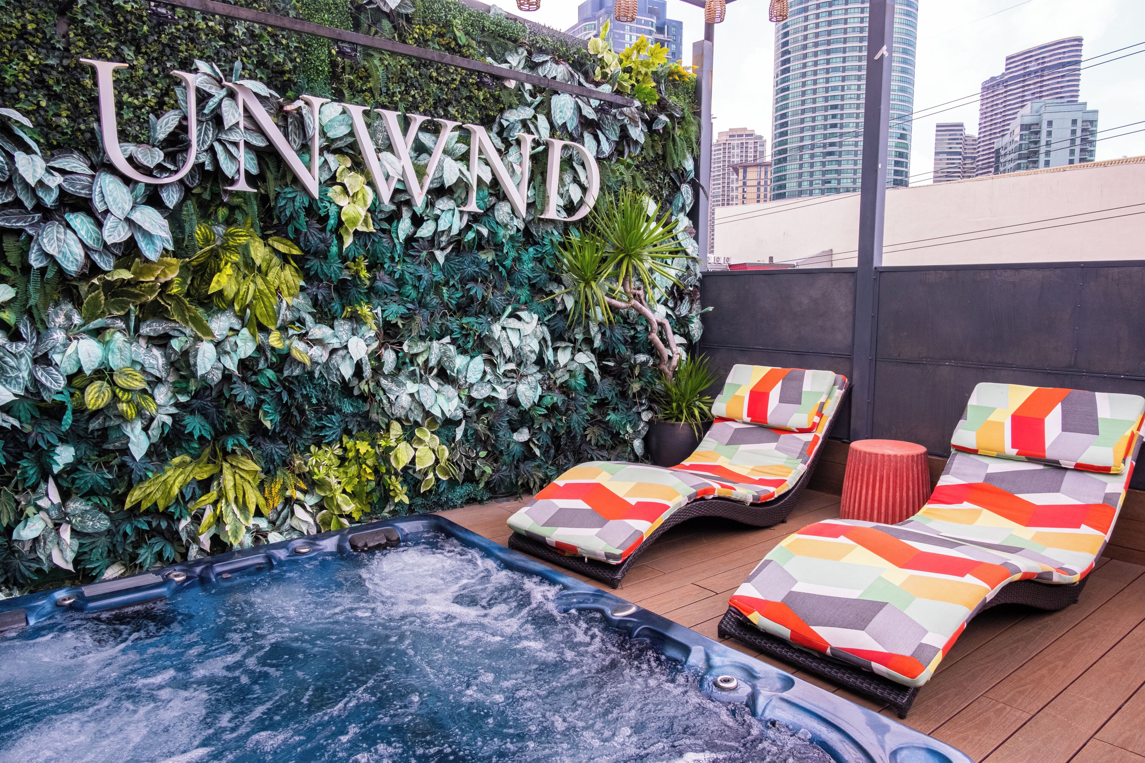 Un espace de détente sur le toit, avec un jacuzzi, des chaises longues et un mur sur lequel est inscrit le mot « RELAX ».