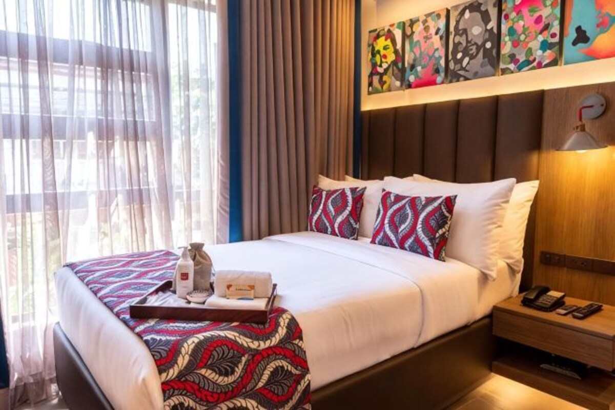 Une chambre d’hôtel avec un lit, une table de chevet et une œuvre d’art au mur.