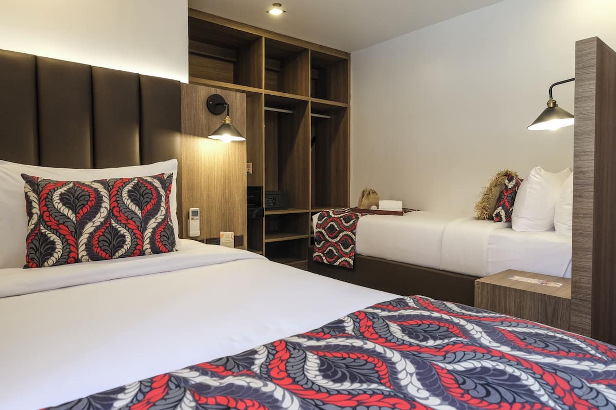 A hotel room with a large bed, a wardrobe, a bedside table, and a small desk.