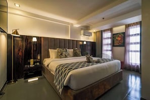 Una moderna camera d'hotel con un letto grande, comodini, una lampada e un quadro appeso al muro.