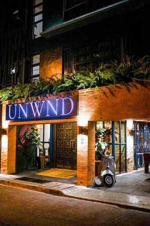 Un edificio con un neon che riporta la scritta 'UNWIND' di sera.