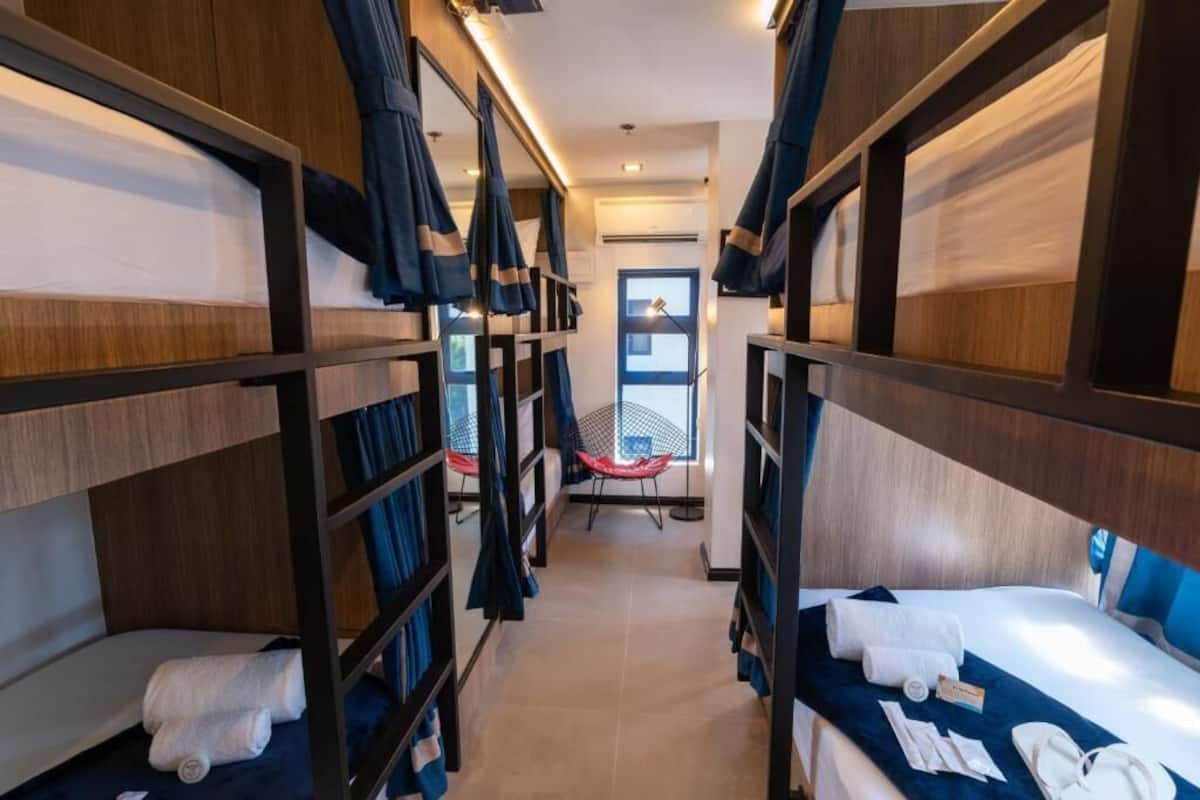 A bunk room with wooden bunk beds, a window, and a red chair.