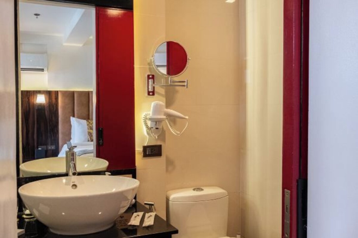 Une salle de bain équipée d’un lavabo, d’un miroir, d’un sèche-cheveux et de toilettes.