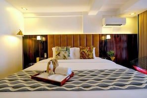 A modern hotel room with a large bed, a bedside table, a chair, and a nightstand.
