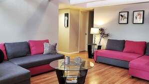 A modern living room with two sofas, a glass coffee table, and a door leading to another room.