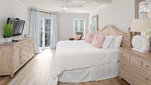 A bedroom with a bed, a TV, a dresser, a lamp, and a ceiling fan. - Completely renovated condominium (St Simons)